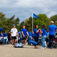 Students throw bean bags at cornhole board during tailgate.